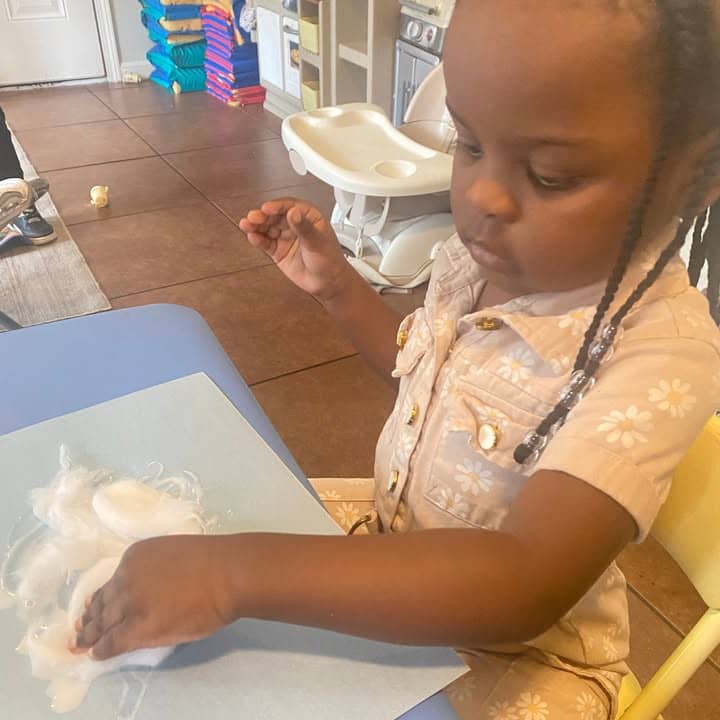 A toddler exploring cotton at the table