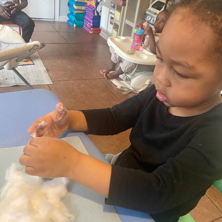 A toddler doing a cotton sensory activity
