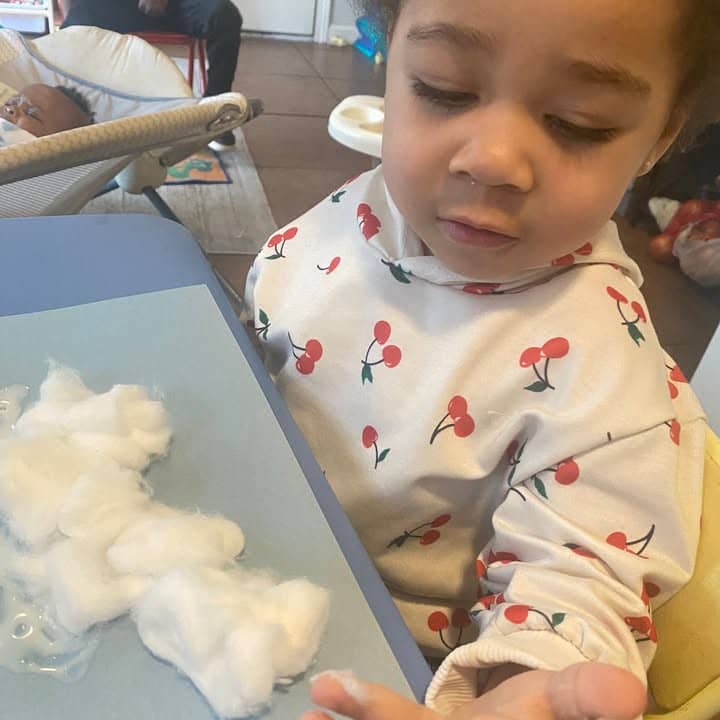 A toddler reaching for cotton during play