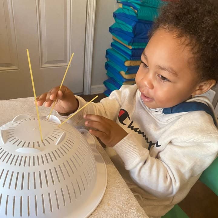 A toddler doing a spaghetti sensory activity